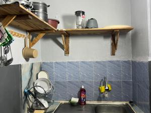 a kitchen with a sink and wooden shelves above it at Beni'o Suite in Adiapo-Doumé