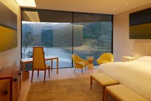um quarto de hotel com uma cama e uma janela grande em Vik Chile em San Vicente de Taguatagua