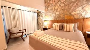 a bedroom with a large bed and a chair at Villa Triacca Hotel Vinícola & Spa in Brasília