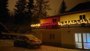 a car parked in front of a house with christmas lights at Tyrolczyk in Szklarska Poręba