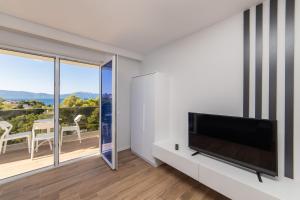 a living room with a flat screen tv and a balcony at Inamore in Gradac