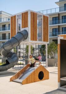 two children sitting on a slide in a playground at Essense Baltic Resort & SPA in Dziwnów