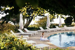 a woman sitting next to a swimming pool at The Atlantic Hotel - Small Luxury Hotels of the World in St. Brelade +67 photos