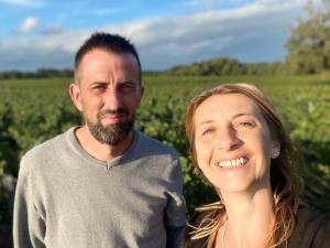 a man and a woman standing in front of a field at L'Amphore du clos de Bigos in Soussans