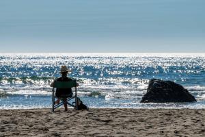 a man sitting in a chair on the beach at Beach Bum Retreat in Cayucos