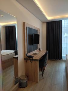 a room with a desk with a television and a bed at Döşemealtı Konfor Hotel in Dosemealti