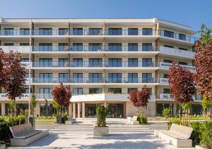 an apartment building with benches in front of it at Essense Baltic Resort & SPA in Dziwnów