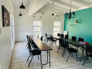 a room with tables and chairs and a green wall at Umsobomvu Guest House in Mthatha