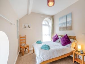 a bedroom with a bed with purple pillows at Golygfa Hudol - Uk46712 in Pwllheli