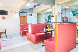 a waiting room with red chairs and a table at Eliper Hotel in Gatura