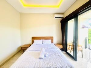 a bedroom with a bed with white sheets at Umah Kak Pasek in Jimbaran