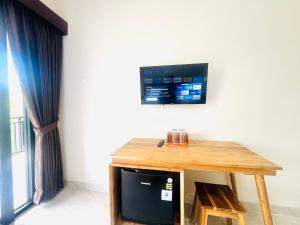 a wooden table with a television on a wall at Umah Kak Pasek in Jimbaran
