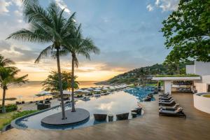 a resort pool with chairs and umbrellas and the ocean at The Ritz-Carlton, Koh Samui in Choeng Mon Beach