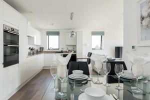 a white kitchen with a glass table and chairs at Beachcliff - On the Seafront with Two Balconies in Bournemouth