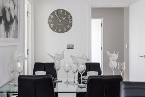 a table with wine glasses and a clock on the wall at Beachcliff - On the Seafront with Two Balconies in Bournemouth +38 photos