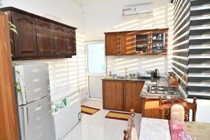a kitchen with wooden cabinets and a white refrigerator at Hureshan Villa in Negombo