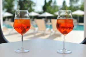 two wine glasses sitting on a table near a pool at Camping Rialto Village in Campalto