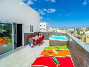 a balcony with a table and a swimming pool at Bayside Apartments in St. Julianʼs