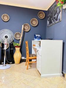a room with a blue wall with a desk and a fan at Esther Villas Home in Boma la Ngombe +44 photos