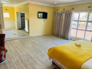 a bedroom with a bed and a tub and a television at Umsobomvu Guest House in Mthatha