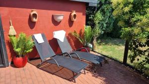 two lawn chairs sitting next to a red wall at Stouwhuset Øster Hurup in Hadsund