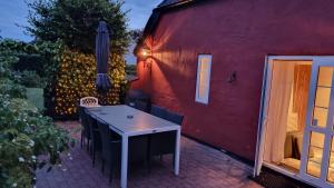 a table and chairs in front of a red building at Stouwhuset Øster Hurup in Hadsund