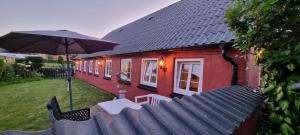 a red house with a table and an umbrella at Stouwhuset Øster Hurup in Hadsund
