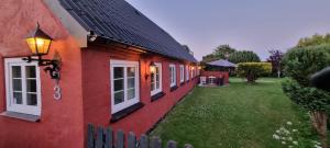 a red house with a fence next to a yard at Stouwhuset Øster Hurup in Hadsund +27 photos