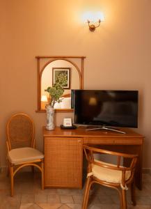 a desk with a television and two chairs and a mirror at Hotel Sirio in Lampedusa