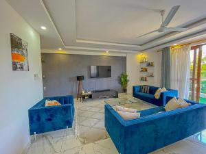 a living room with blue couches and a tv at Aqua Epic Residence in Mombasa