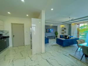 a living room with a blue couch and a kitchen at Aqua Epic Residence in Mombasa