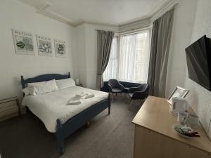 a bedroom with a bed and a desk with a television at Glen Allan Hotel in Blackpool