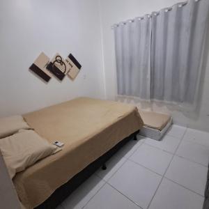a small bedroom with a bed and a window at Conforto e Lazer! Casa com Piscina e 3 Quartos in Palmas