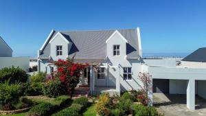 a white house with flowers in the yard at Salt & Butter in Hermanus