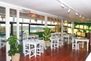 a restaurant with white tables and chairs and windows at Issaquena Heights Boutique Hotel in Knysna