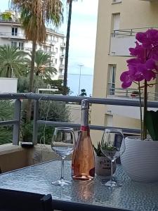 a bottle of wine and two glasses on a table at One minute to the Beach in Menton