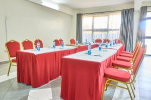 a row of tables in a room with red chairs at Eliper Hotel in Gatura