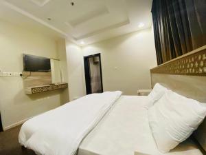 a bedroom with a white bed and a television at Emaar million6 in Quai