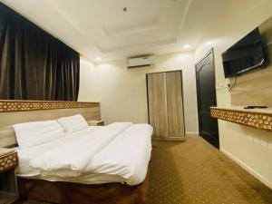 a bedroom with a white bed and a flat screen tv at Emaar million6 in Quai