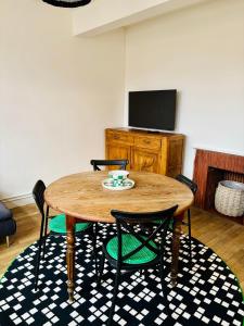 a wooden table with chairs and a television in a room at Le beffroi in Abbeville