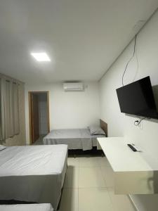 a hotel room with two beds and a flat screen tv at AL&V Hotel in Santa Tereza do Oeste