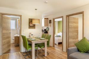a dining room and living room with a table and green chairs at Ferienhaus Biber im Sternenpark in Lochow