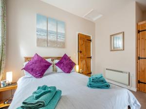 a bedroom with a large white bed with purple pillows at Golygfa Hudol - Uk46712 in Pwllheli +11 photos