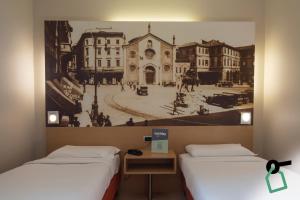 two beds in a room with a picture on the wall at Hotiday Milano Navigli in Milan