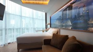 a bedroom with a bed and a couch and a large window at Smart Hotel Thamrin Jakarta in Jakarta