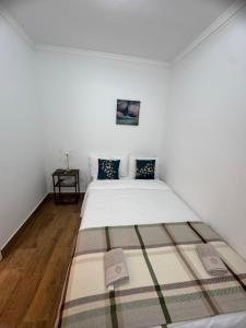 a white bedroom with a bed with a rug on the floor at Cascais Garden House 103 in Cascais