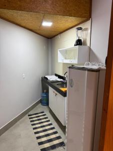 a small kitchen with a counter and a refrigerator at Chalé Anjos Mar in Barrinha