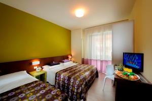 a hotel room with two beds and a table at Hotel Luciana in Bibione +56 photos