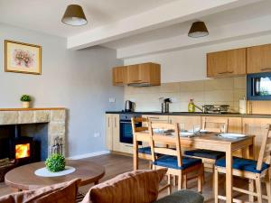 a kitchen and dining room with a table and a fireplace at The Coolins cottage with wood burner in Strathcarron