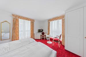 ein Schlafzimmer mit einem weißen Bett, einem Tisch und Stühlen in der Unterkunft Hotel Mozart in Rorschach